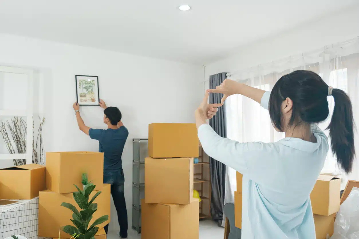 Couple unpacking and hanging framed artwork in new home during residential move